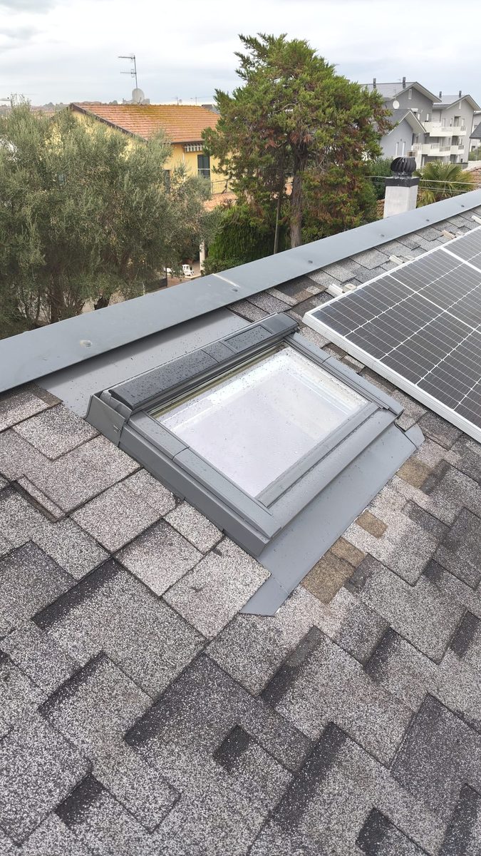 Finestra VELUX solare installata su tetto in tegole canadesi accanto ai pannelli fotovoltaici a Giulianova